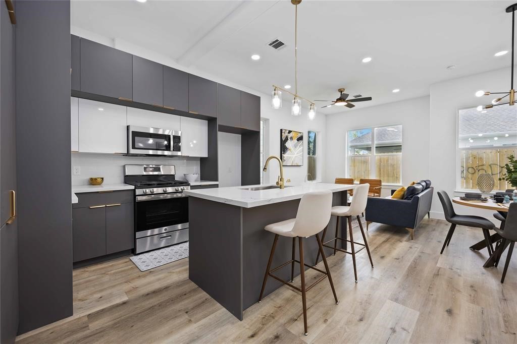 1805 Emir Street, Unit M Houston, TX 77009 - Photo 7 of 35 a kitchen with stainless steel appliances kitchen island granite countertop a refrigerator a stove a sink a dining table and chairs with wooden floor