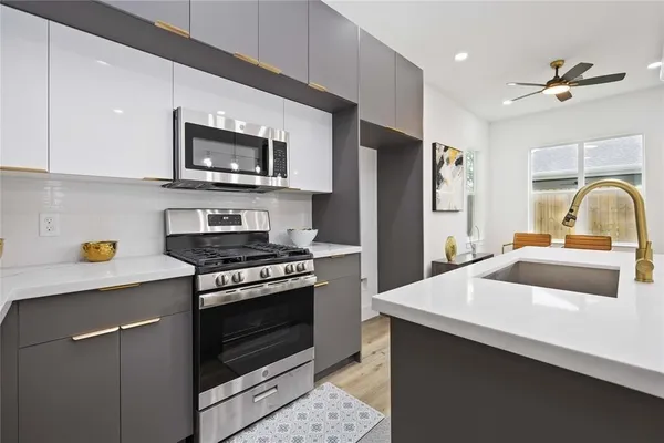 a kitchen with stainless steel appliances kitchen island granite countertop a refrigerator a stove a sink a dining table and chairs with wooden floor