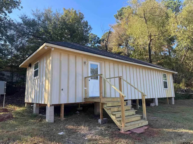 a view of a small house with backyard and sitting area