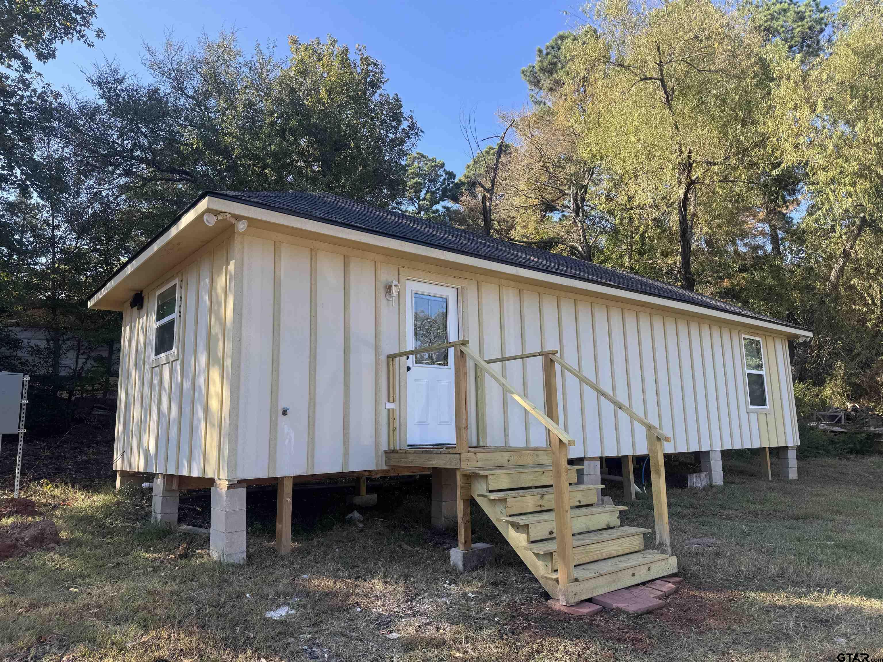 a view of a small house with backyard and sitting area