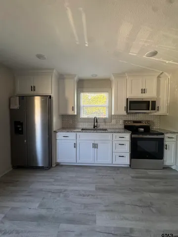 a kitchen with stainless steel appliances granite countertop a refrigerator and a stove top oven