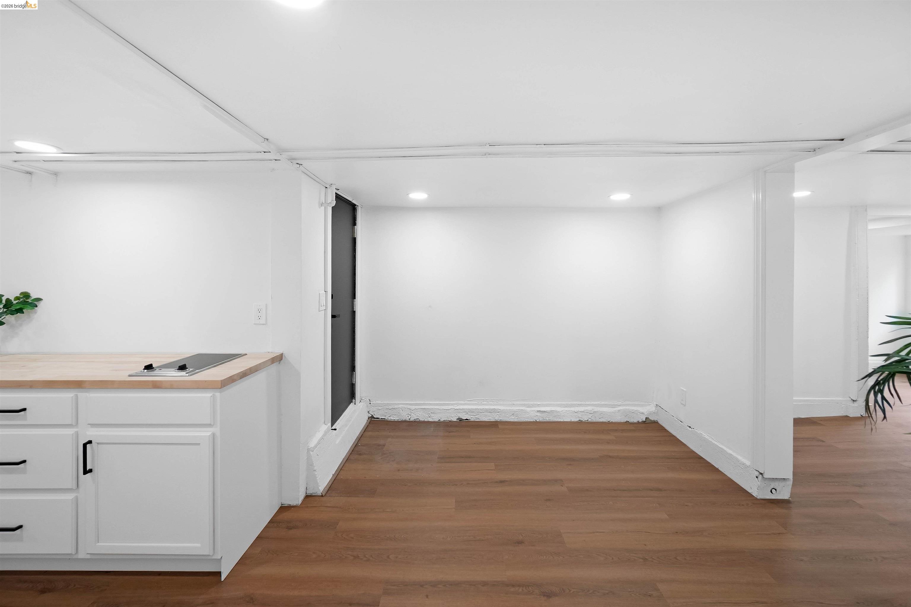 1812 Woolsey Street Berkeley, CA 94703 - Photo 34 of 48 Compact kitchen area featuring white cabinetry with black hardware, a light wood-finish countertop, and an integrated cooktop