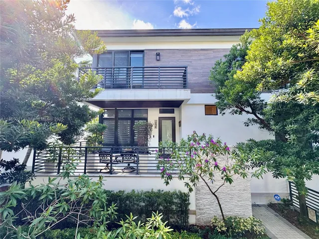 a view of a house with potted plants and large trees