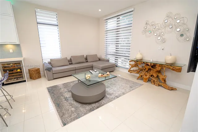 a living room with stainless steel appliances kitchen island granite countertop a sink and a refrigerator