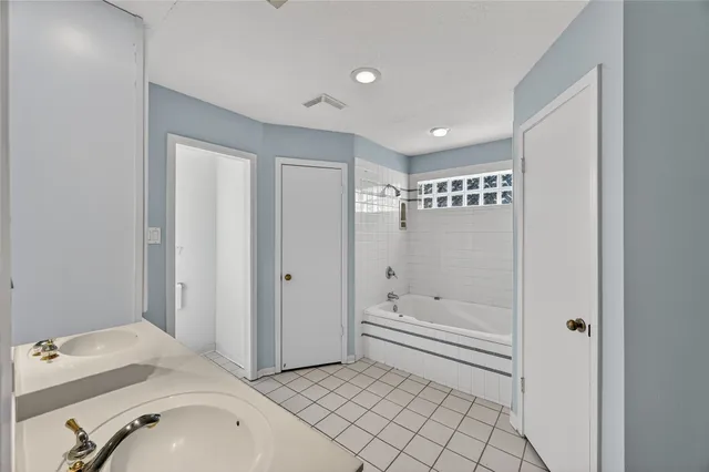 a bathroom with a tub a sink and a large mirror