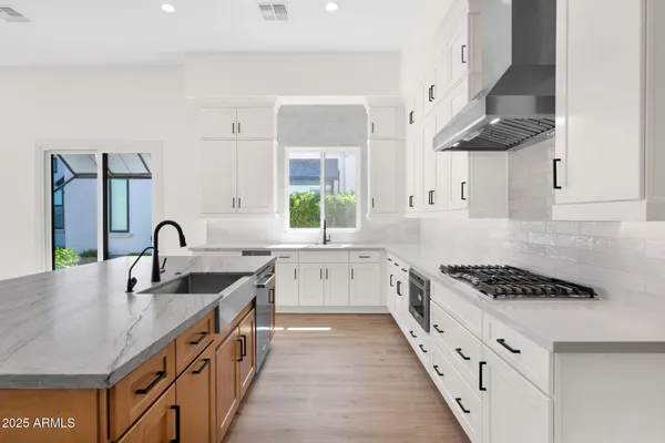 a kitchen with stainless steel appliances granite countertop a sink a stove and a wooden floors