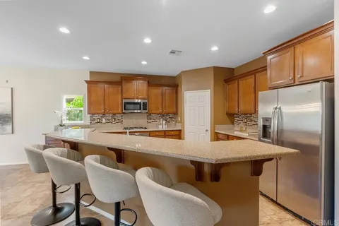 a kitchen with stainless steel appliances granite countertop a table chairs sink refrigerator and microwave