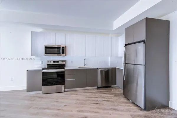 a kitchen with granite countertop a refrigerator and a stove top oven