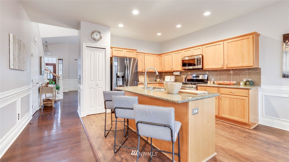 16013 Southeast 137th Terrace Renton, WA 98059 - Photo 14 of 40 a kitchen with stainless steel appliances granite countertop a refrigerator a stove top oven and a dining table with wooden floor