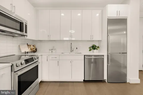 a kitchen with cabinets stainless steel appliances and wooden floor