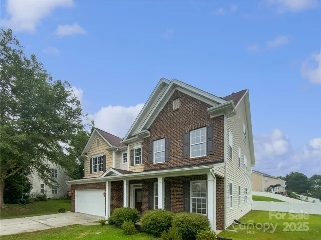 a view of a white house with a big yard and potted plants and trees