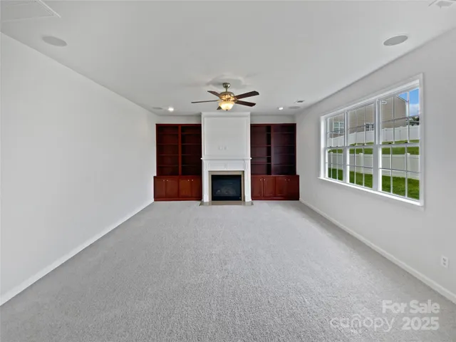 a view of a livingroom with a fireplace a ceiling fan and window