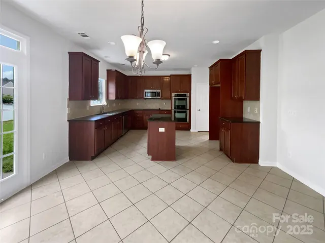 a kitchen with stainless steel appliances granite countertop a refrigerator and a wooden cabinets