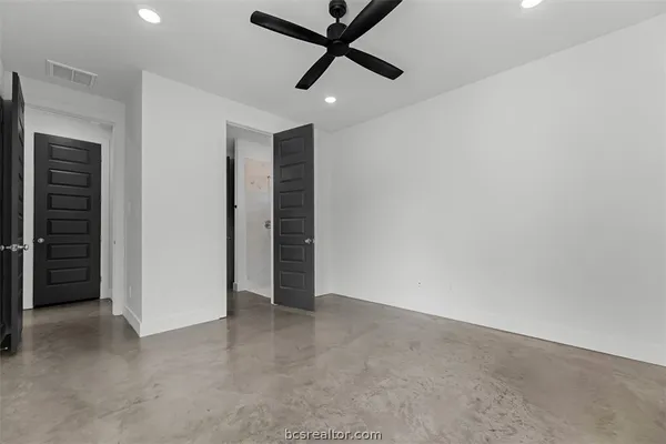 an empty room with closet and a ceiling fan