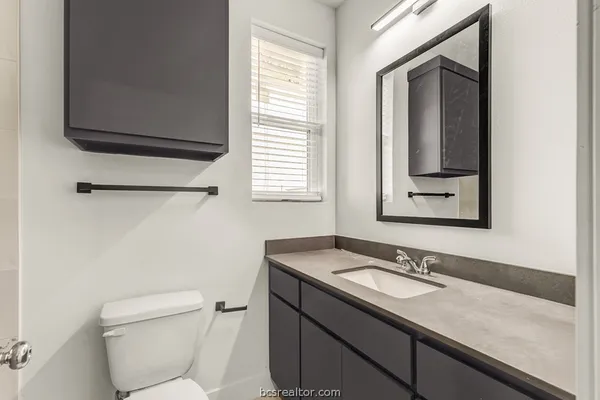 a bathroom with a granite countertop sink and a toilet