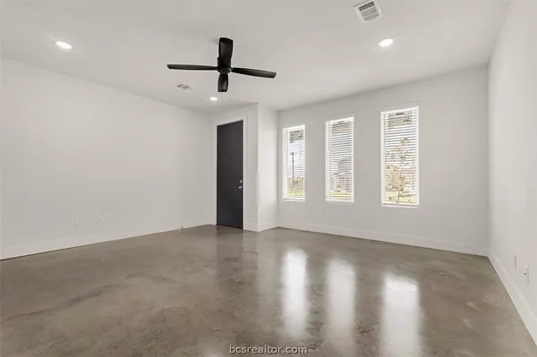 a view of an empty room with a window and wooden floor