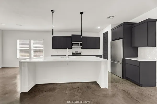 a kitchen with stainless steel appliances kitchen island granite countertop a refrigerator a oven a sink with a dining table and chairs