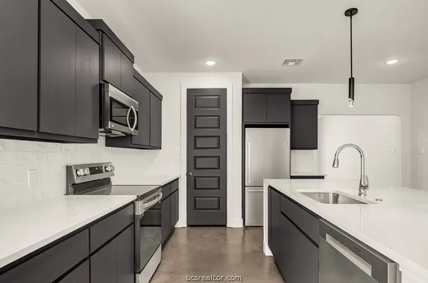 a kitchen with stainless steel appliances a sink a stove a refrigerator and cabinets
