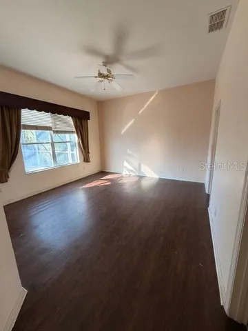 a view of an empty room with wooden floor and a window