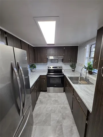 a kitchen with stainless steel appliances granite countertop a sink stove and refrigerator