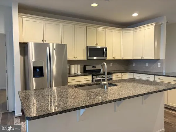 a kitchen with stainless steel appliances granite countertop a sink a refrigerator and a granite counter tops