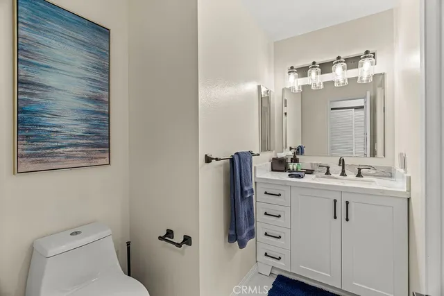 a bathroom with a toilet sink vanity and mirror