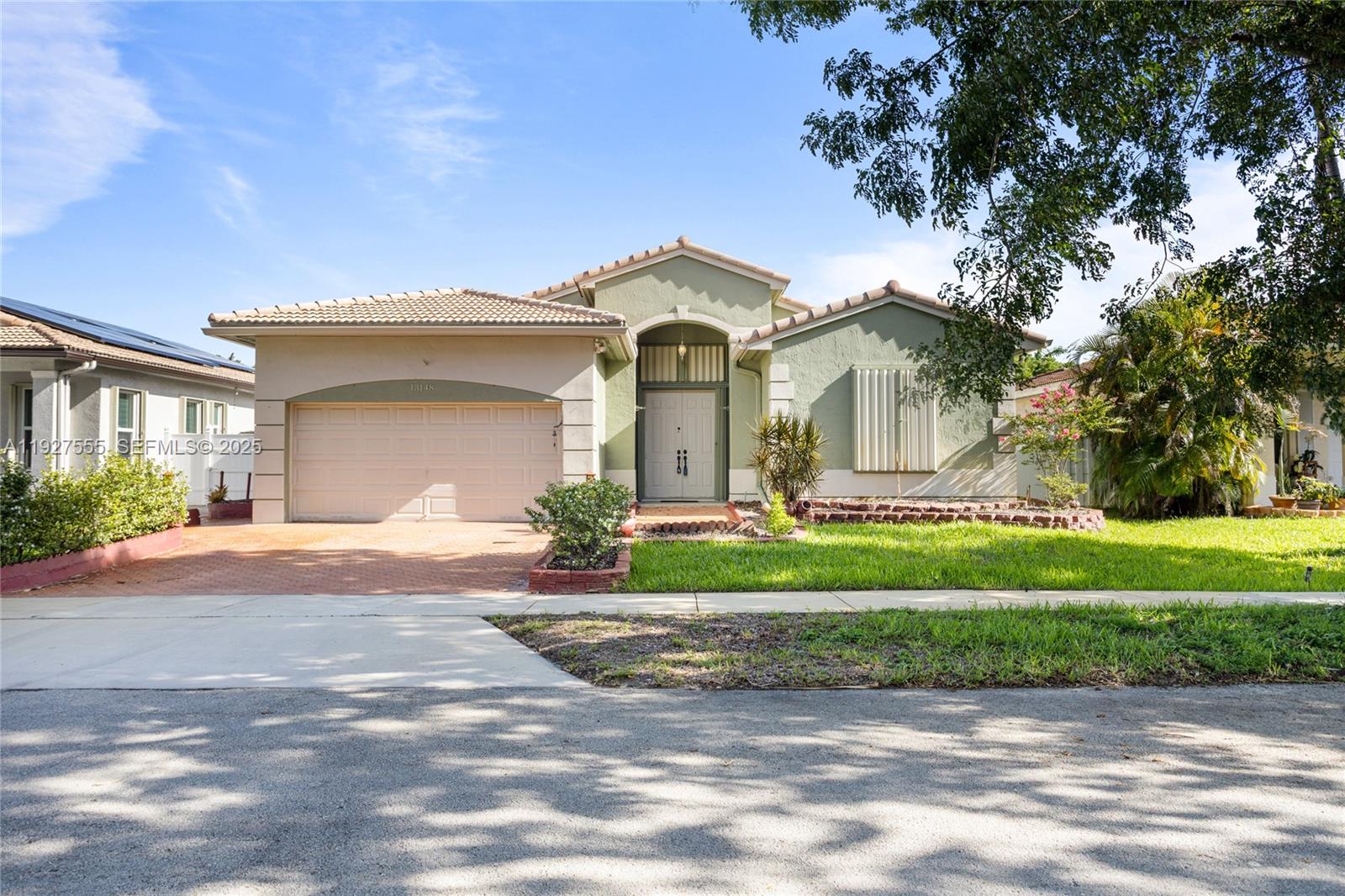 13148 Southwest 23rd Street Miramar, FL 33027 - Photo 1 of 24 a front view of a house with a garden and tree