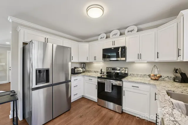 a kitchen with granite countertop a refrigerator stove and sink