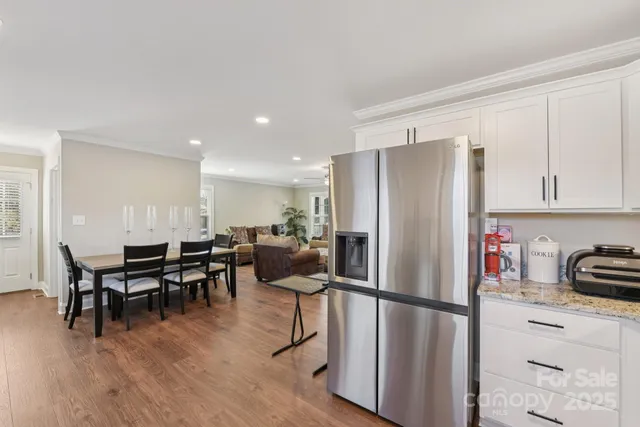 a kitchen with stainless steel appliances a refrigerator a stove a dining table and chairs with wooden floor