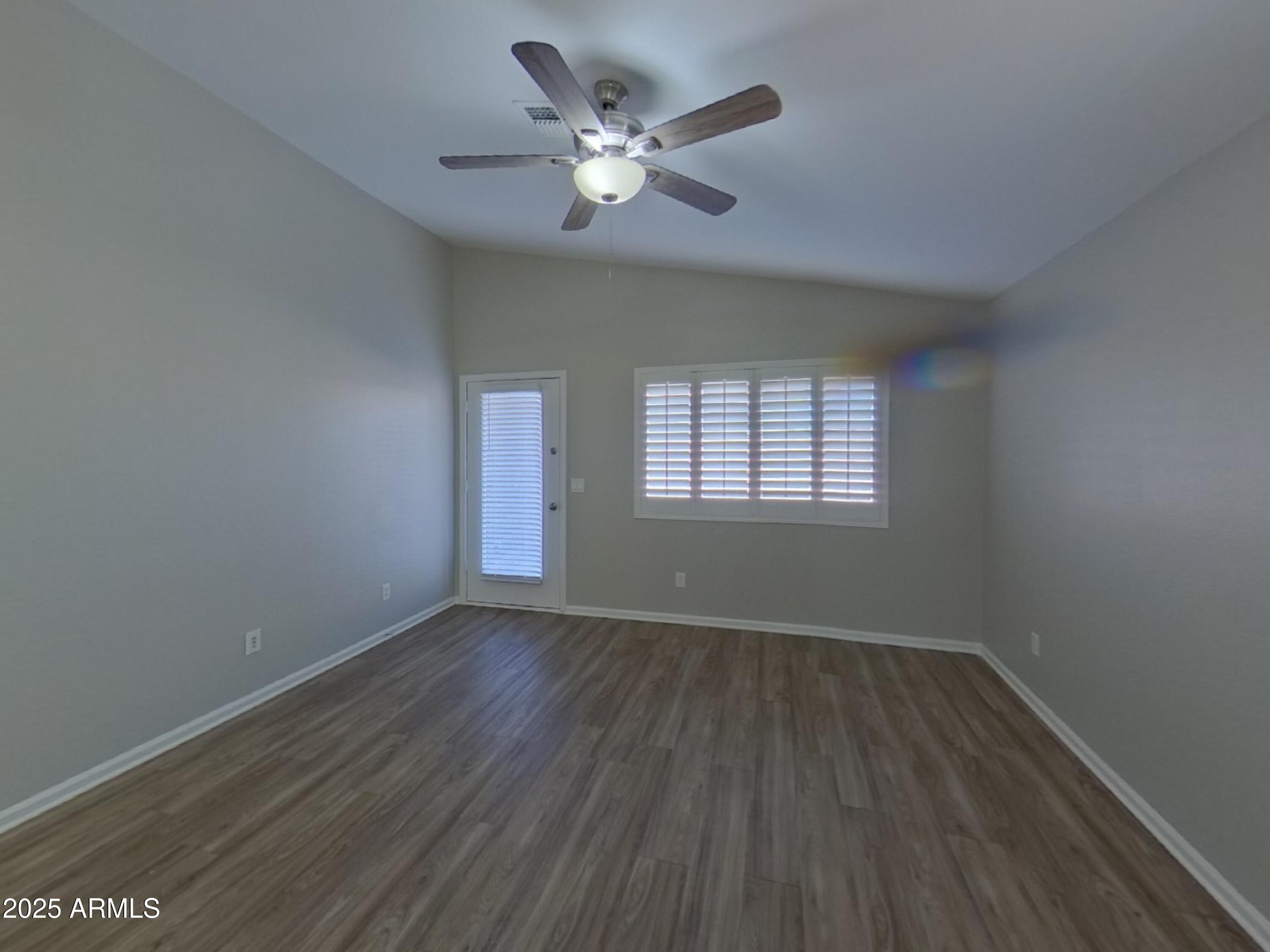 42396 Colby Drive Maricopa, AZ 85138 - Photo 3 of 17 an empty room with wooden floor chandelier fan and windows