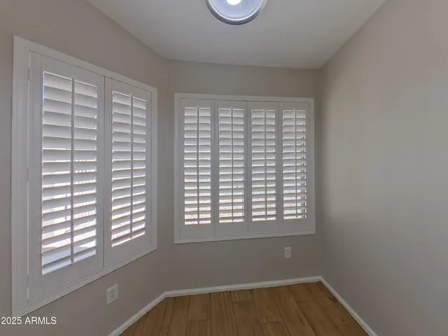 an empty room with wooden floor chandelier fan and windows