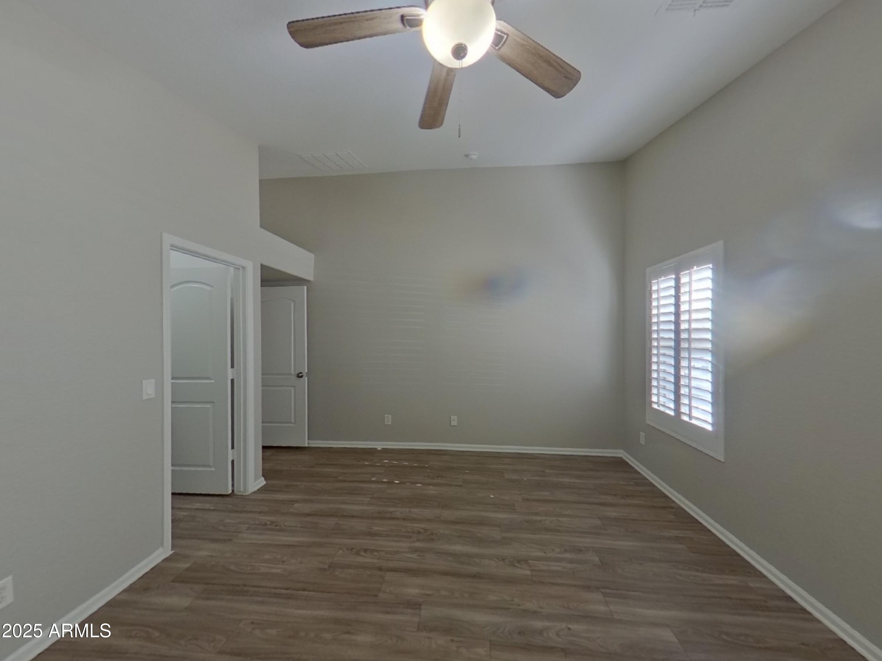 42396 Colby Drive Maricopa, AZ 85138 - Photo 7 of 17 an empty room with wooden floor and windows