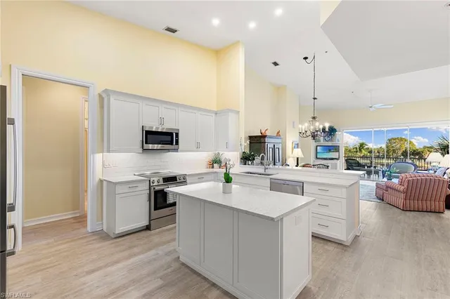 a kitchen with stainless steel appliances a sink a stove a refrigerator cabinets and living room view