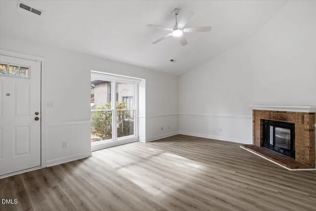 an empty room with wooden floor fan and windows