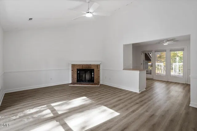 an empty room with wooden floor fireplace and windows
