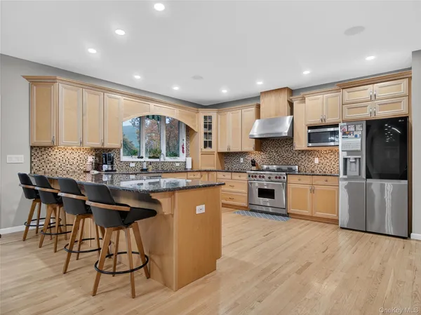 a kitchen with stainless steel appliances granite countertop a stove top oven a refrigerator a sink and a dining table with wooden floor