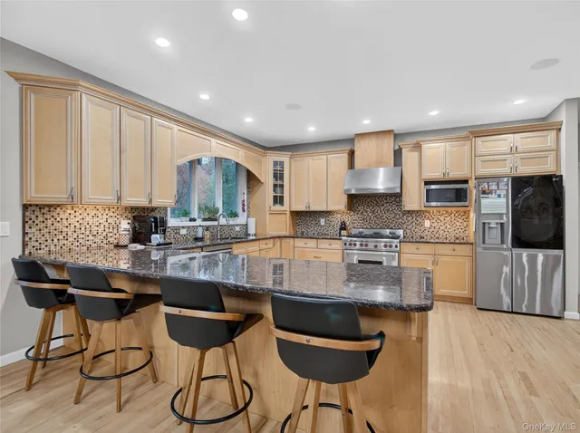 a kitchen with stainless steel appliances granite countertop a stove a sink a microwave a dining table and chairs