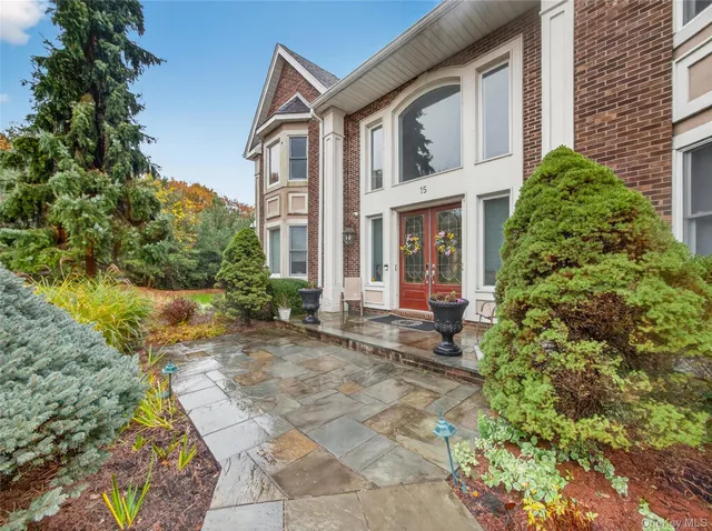 a view of a brick house with plants and large tree