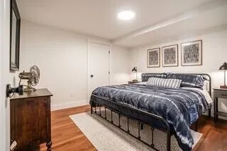 a bedroom with a bed and a dresser with wooden floor