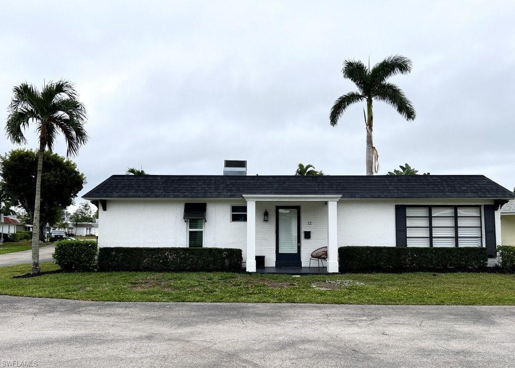 12 Knights Bridge Road, Unit A32 Naples, FL 34112 - Photo 15 of 17 a front view of a house with a yard and garage
