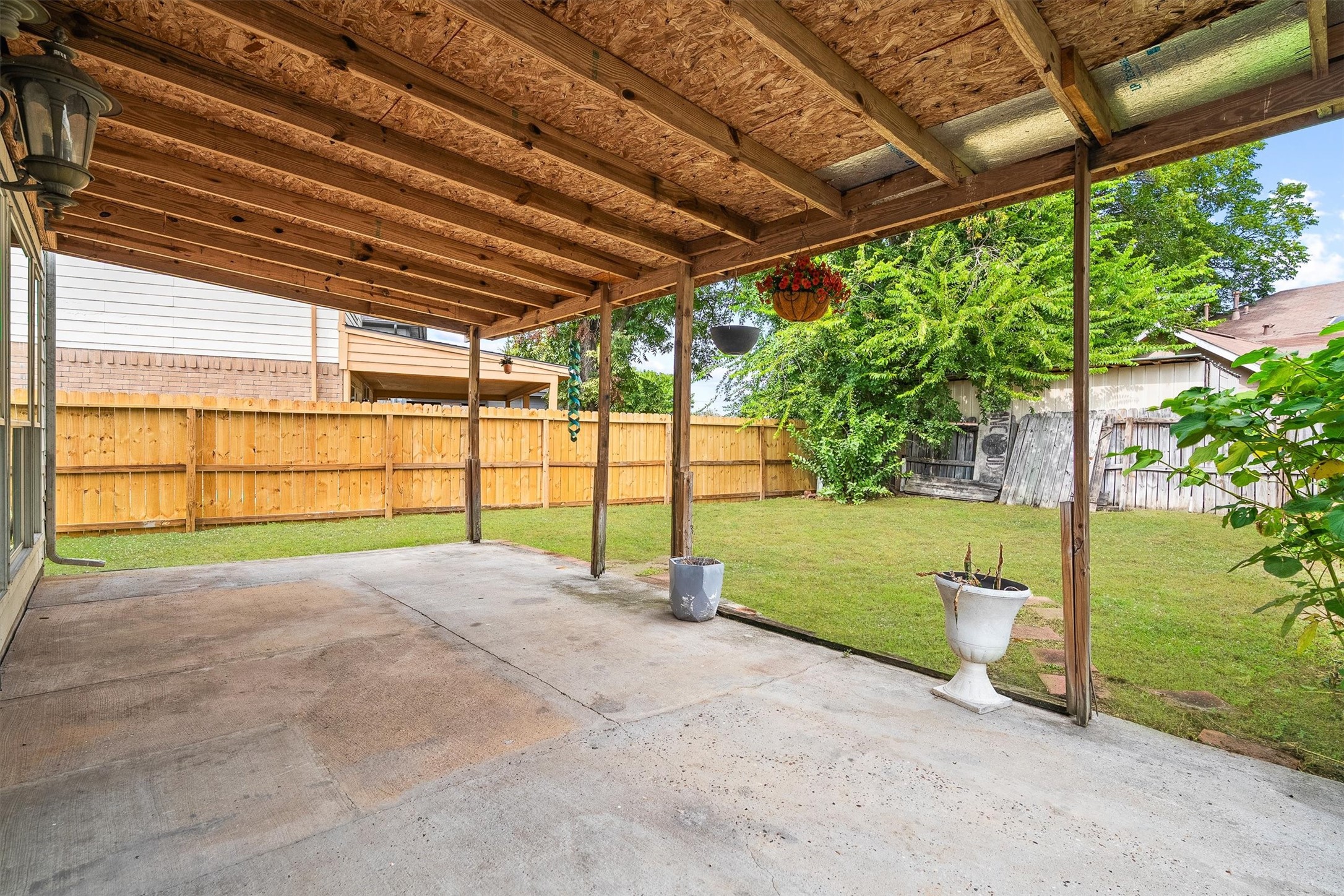 5426 Bourgeois Road Houston, TX 77066 - Photo 19 of 43 Experience outdoor relaxation in this covered patio space, perfect for entertaining, overlooking a spacious fenced backyard with lush greenery.