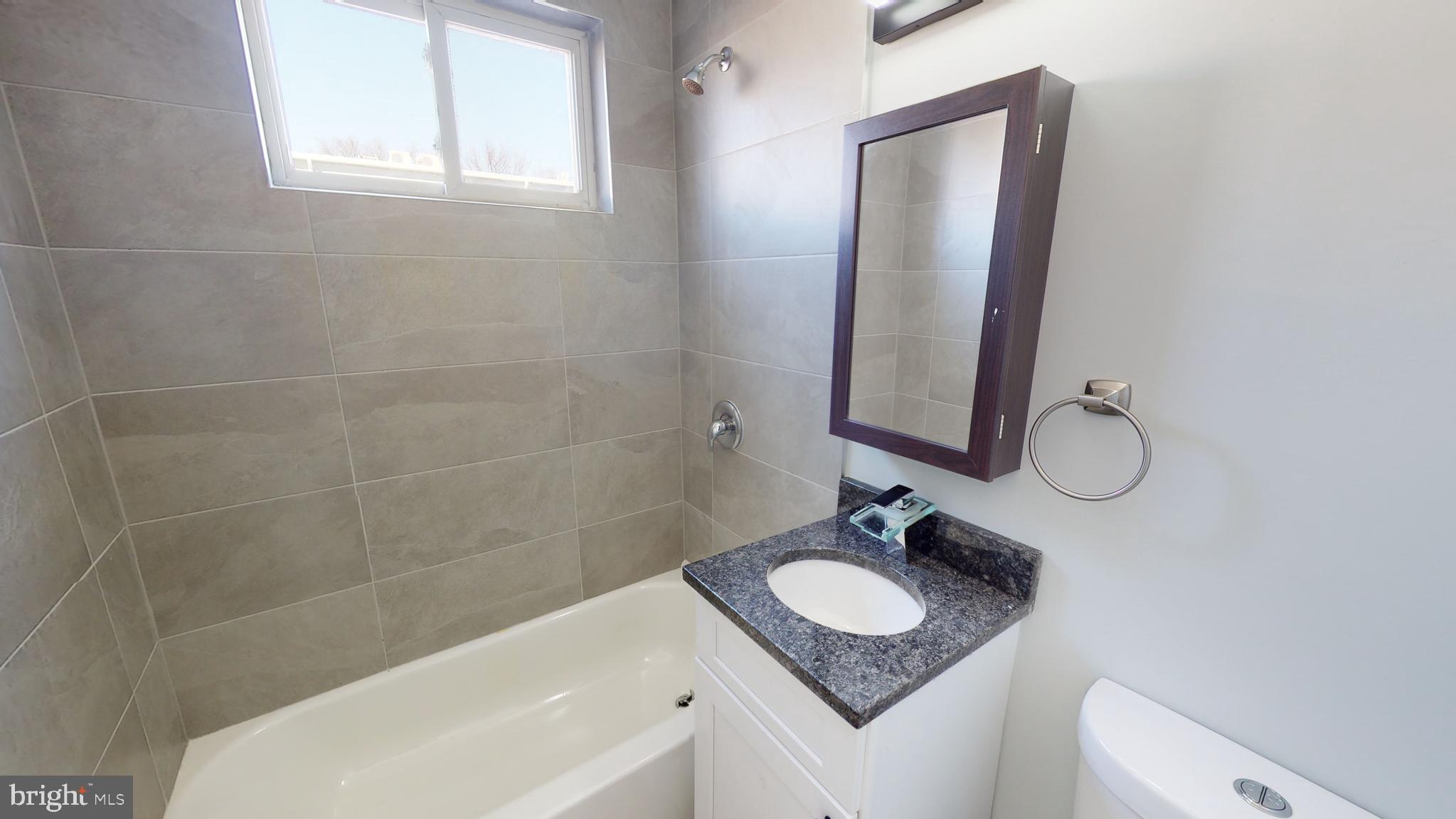 910 Gateway Boulevard, Unit A2 Westville, NJ 08093 - Photo 9 of 12 a bathroom with a granite countertop sink mirror and a bathtub