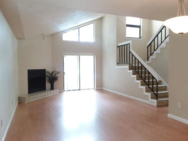 a view of an empty room with wooden floor and stairs