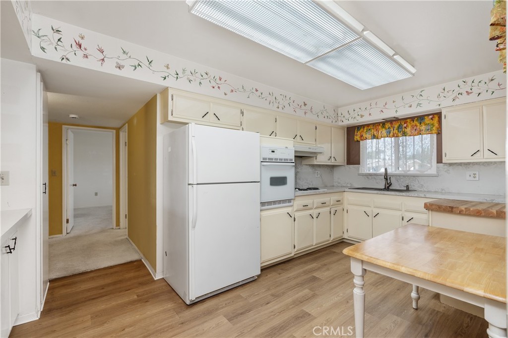 28121 Pebble Beach Drive Menifee, CA 92586 - Photo 11 of 35 a kitchen with granite countertop a refrigerator a sink and white cabinets