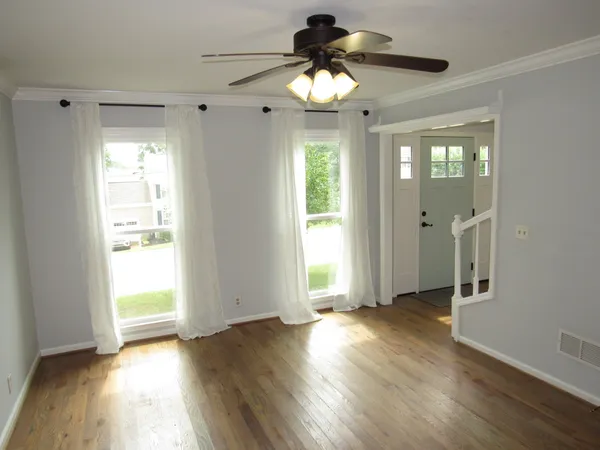 an empty room with wooden floor and windows
