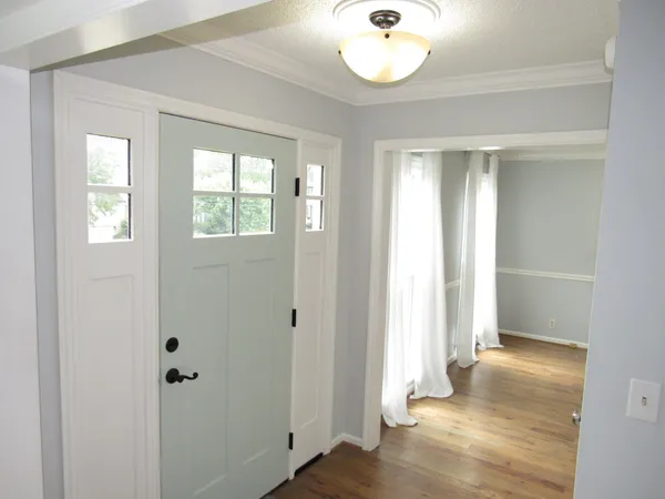 a view of an empty room with wooden floor fireplace and a window