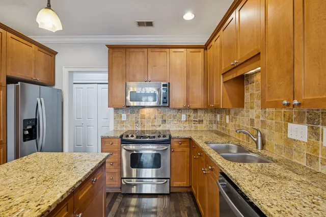 a kitchen with stainless steel appliances granite countertop a sink a stove and a wooden floors