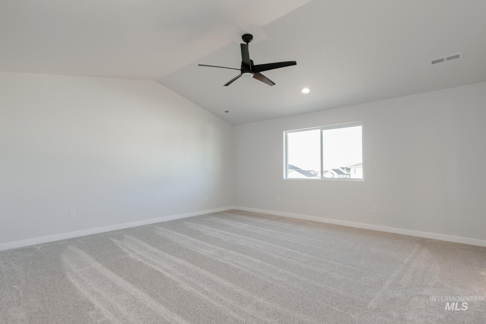 1639 Celina Street Middleton, ID 83644 - Photo 10 of 19 Spacious room featuring vaulted ceilings, light-toned carpeting, a contemporary black ceiling fan, and a large window providing ample ambient light