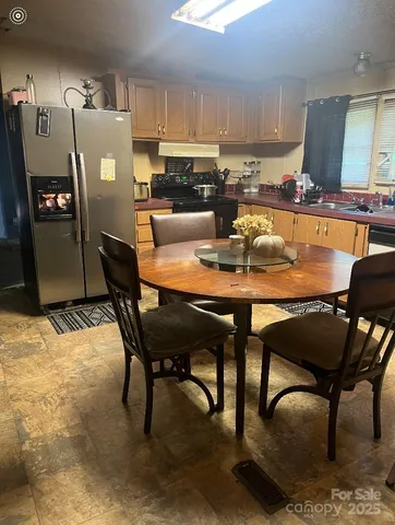 a dining room with stainless steel appliances kitchen island granite countertop a table chairs and a refrigerator