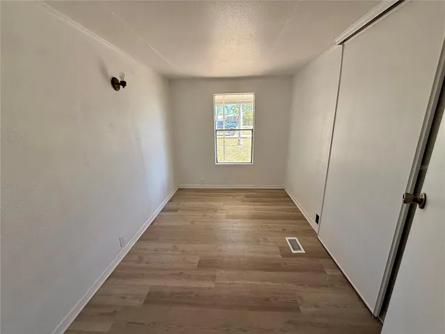 a view of a hallway with wooden floor and window